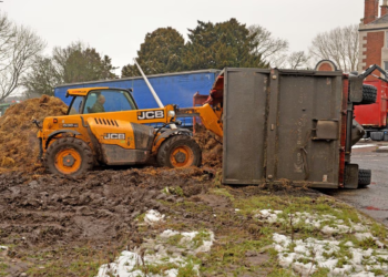 Toppled trailer dumps manure near busy roundabout