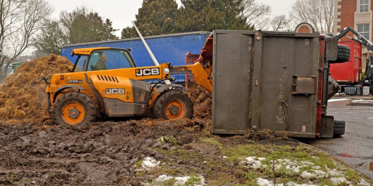 Toppled trailer dumps manure near busy roundabout